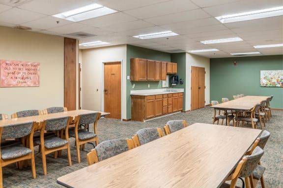 A spacious meeting room with tables, chairs, and a kitchenette.