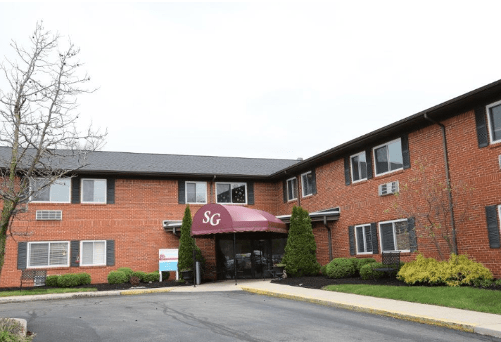 A brick residential building with an entrance featuring a maroon awning labeled '36'.