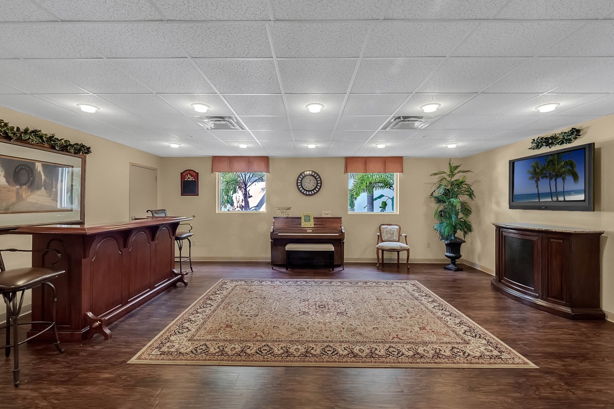 A spacious lobby with wooden flooring, featuring a reception desk, a large carpet, and comfortable seating.