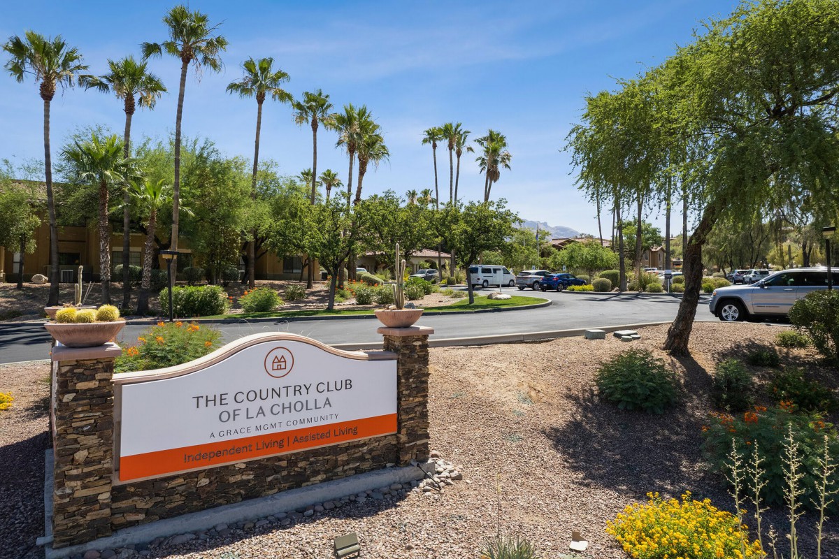 Entrance sign to The Country Club at La Quinta surrounded by palm trees on a sunny day.