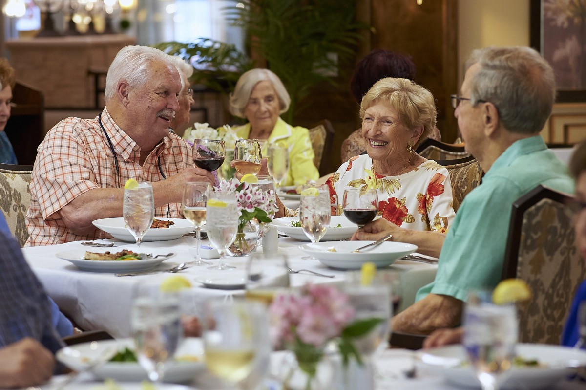 A group of seniors enjoying a meal together, sharing drinks and laughter.