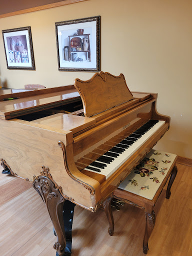 A beautifully crafted wooden grand piano, elegantly placed in a cozy room.
