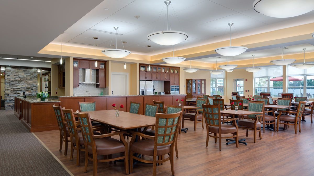 A spacious dining area with wooden tables and chairs, well-lit with modern ceiling lights.