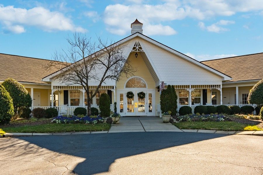 A charming white residential building with a landscaped entrance and clear blue skies.