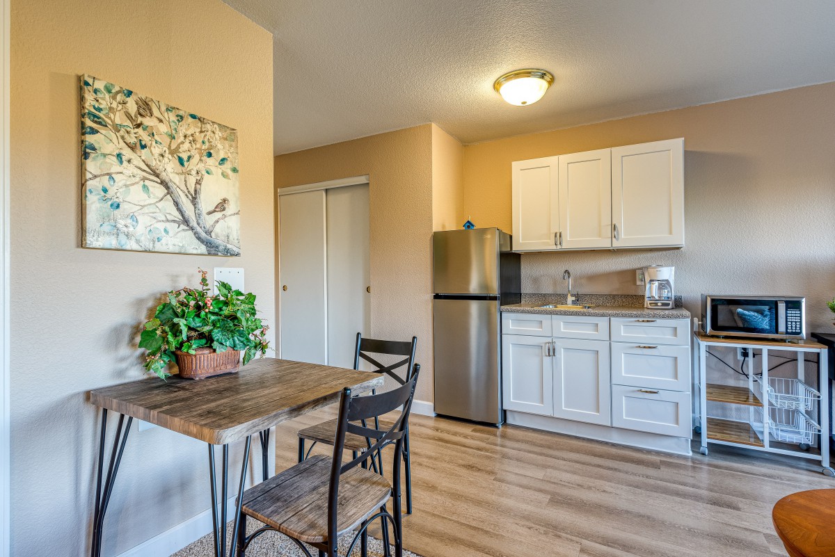 A cozy kitchen and dining area with a small table, chairs, a refrigerator, and cabinets.