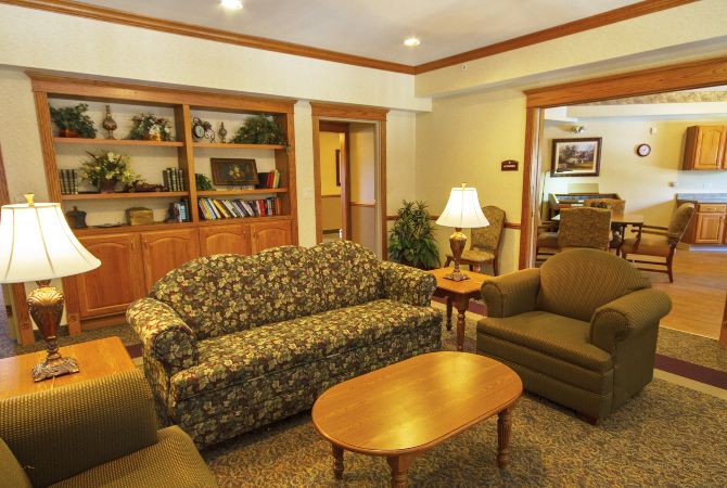 A cozy living room with a patterned sofa, armchairs, and bookshelves.