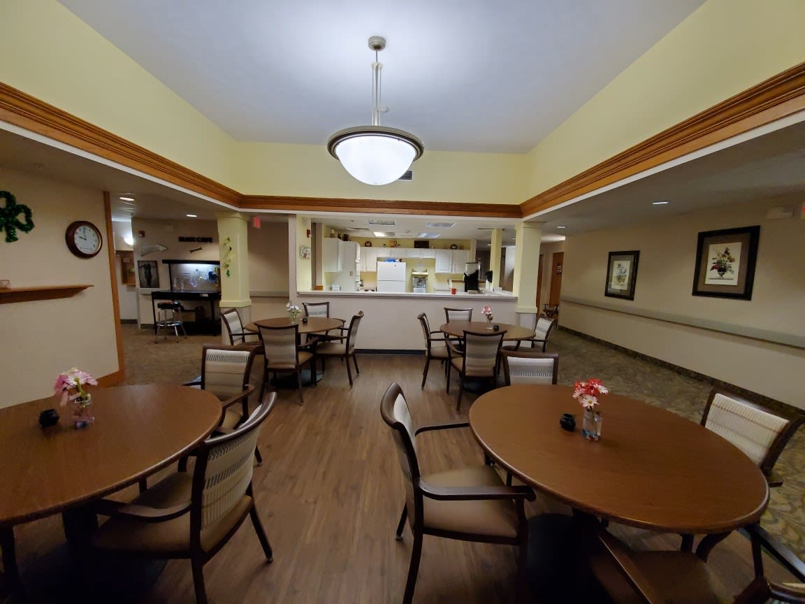A spacious dining area with multiple tables and chairs, featuring warm lighting and a cozy atmosphere.