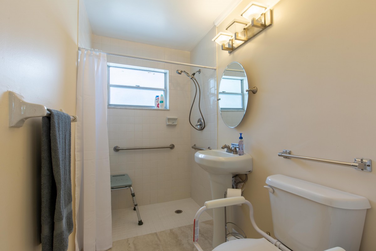 Accessible bathroom with a shower, sink, and toilet equipped with grab bars.