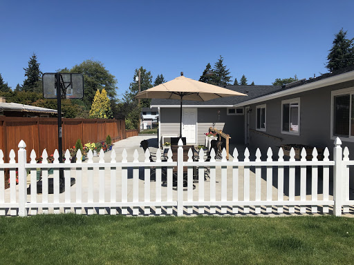 A cozy backyard with a white picket fence and an umbrella on a sunny day.
