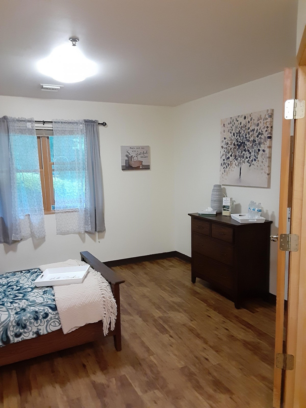 A cozy bedroom with a wooden bed, dresser, and simple decor.