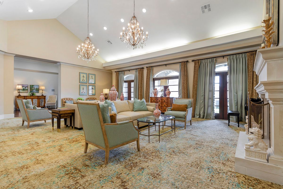 A spacious and elegantly furnished living room with chandeliers, comfortable seating, and large windows.