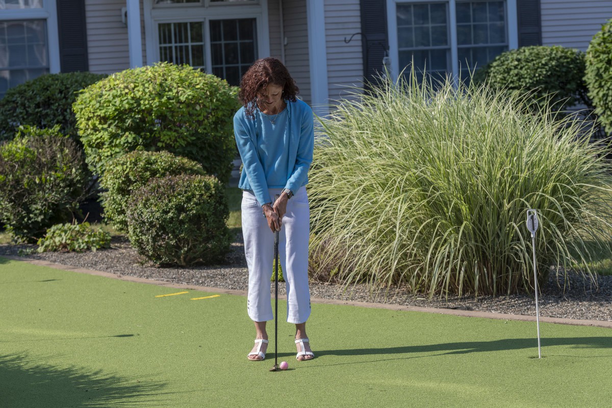 A woman playing golf on a putting green outside during the day.