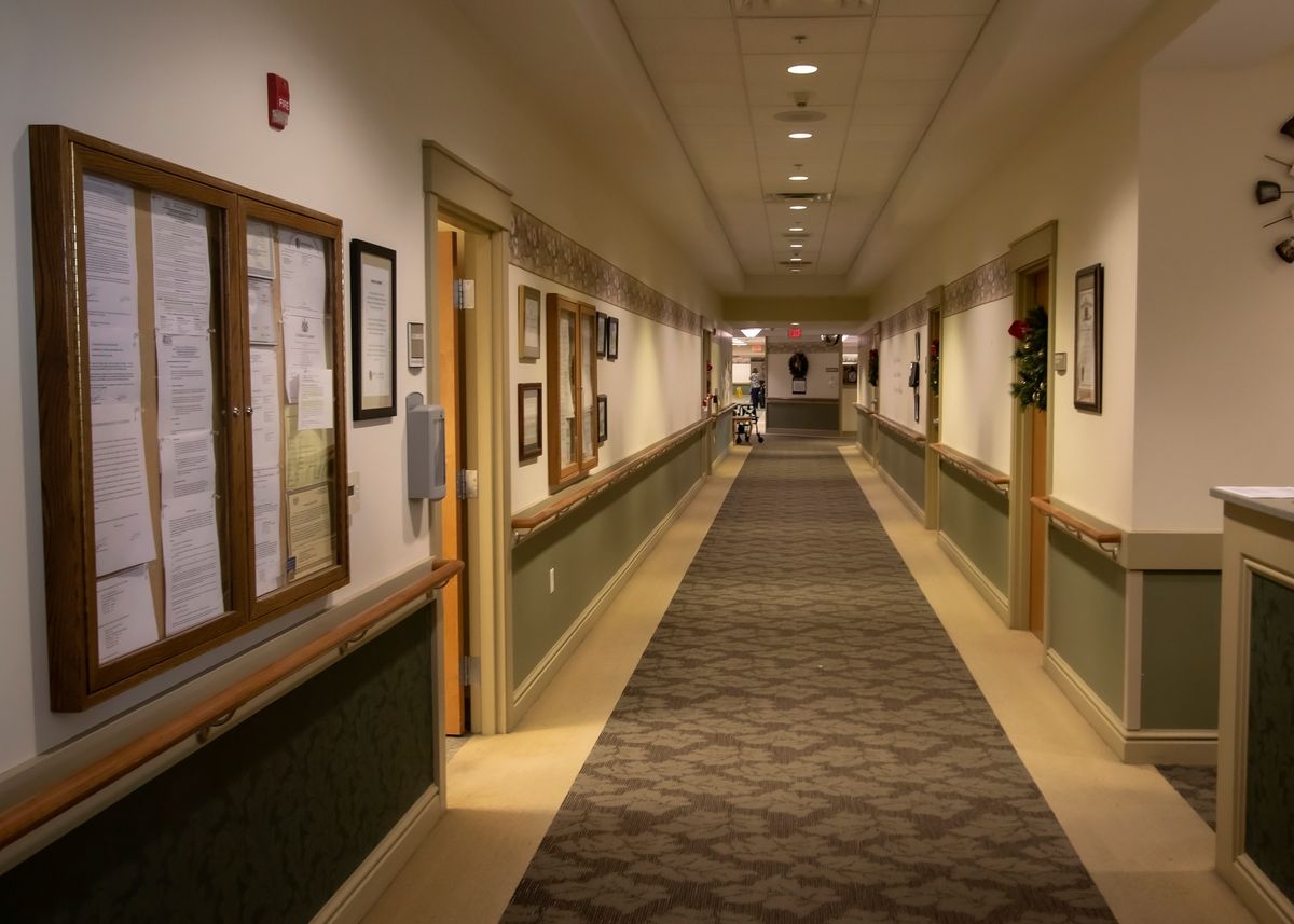 A long, well-lit hallway in an office building with framed pictures on the walls.