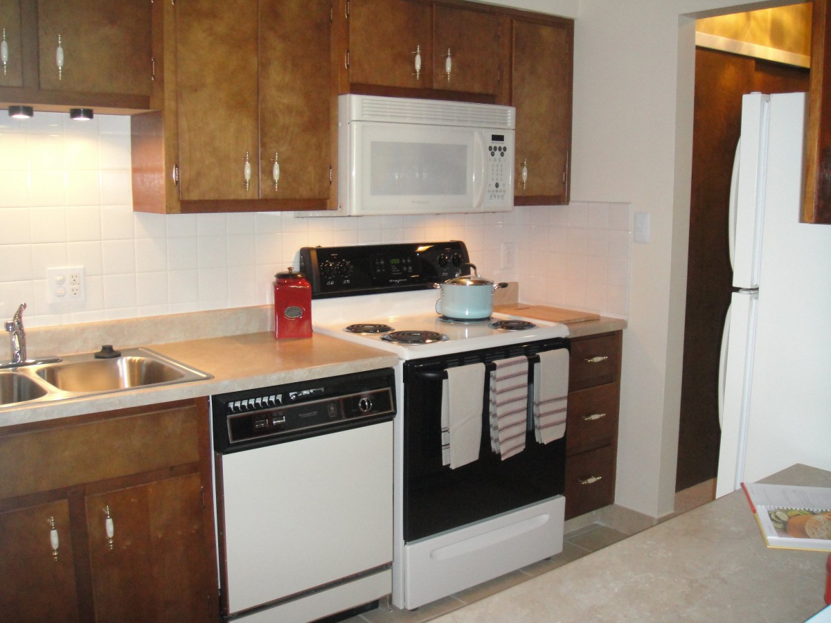 A modern kitchen featuring wooden cabinets, an oven with a stovetop, a microwave, and a dishwasher.