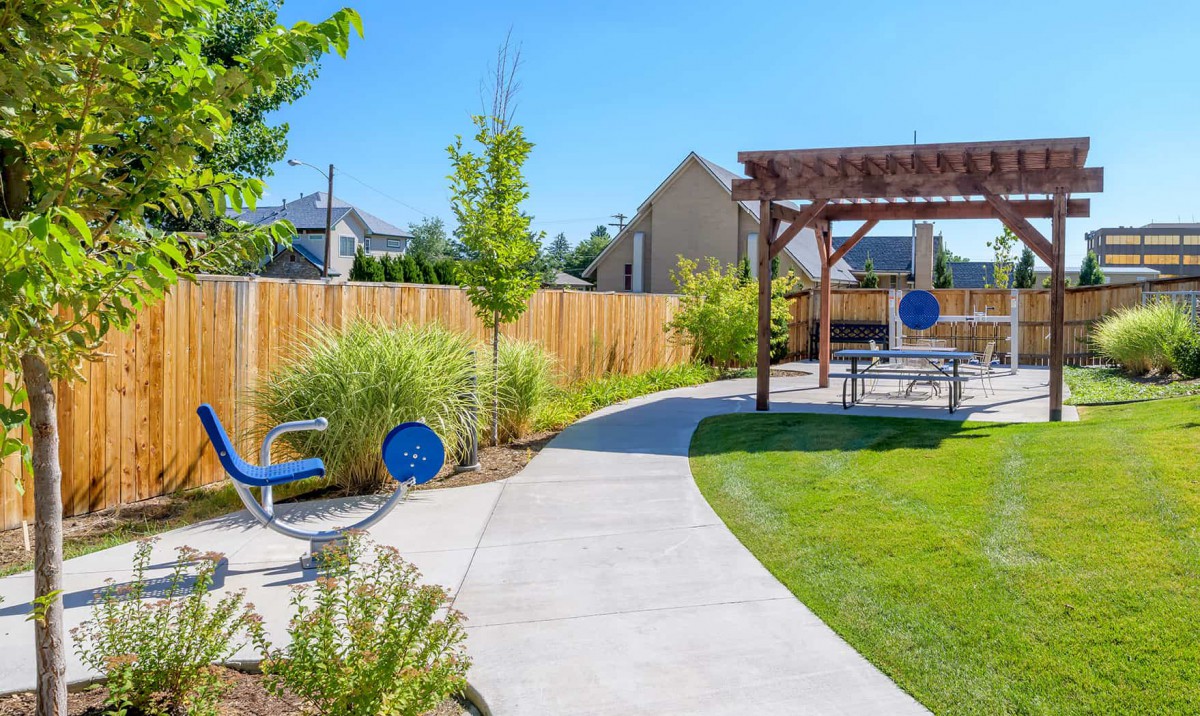 A beautifully landscaped garden with a winding pathway leading to a pergola on a sunny day.