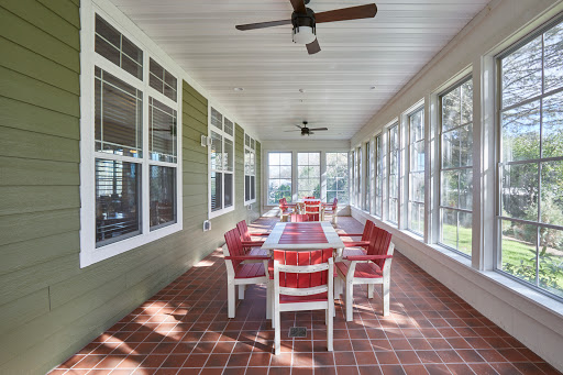 A spacious screened-in porch featuring a long dining table and comfortable chairs, perfect for gatherings.