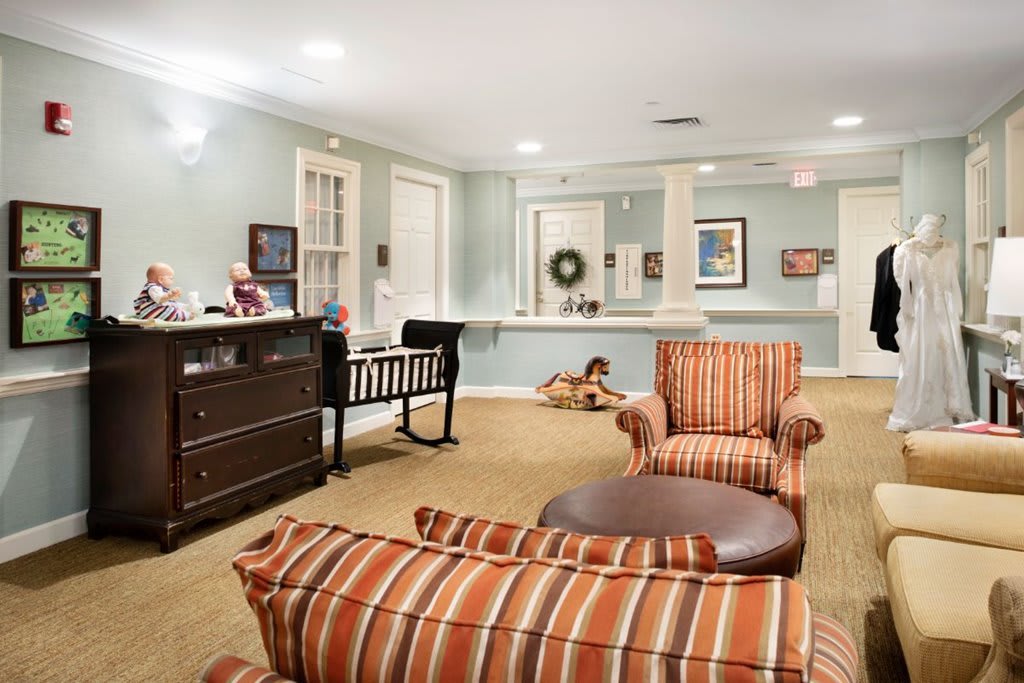 A cozy living room featuring striped armchairs, a crib, and elegant decor.