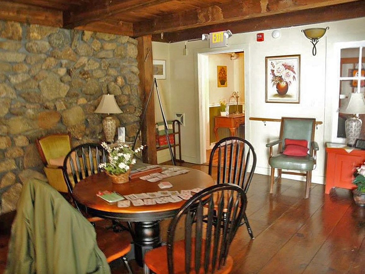 A cozy dining room with wooden furniture and a rustic stone wall.