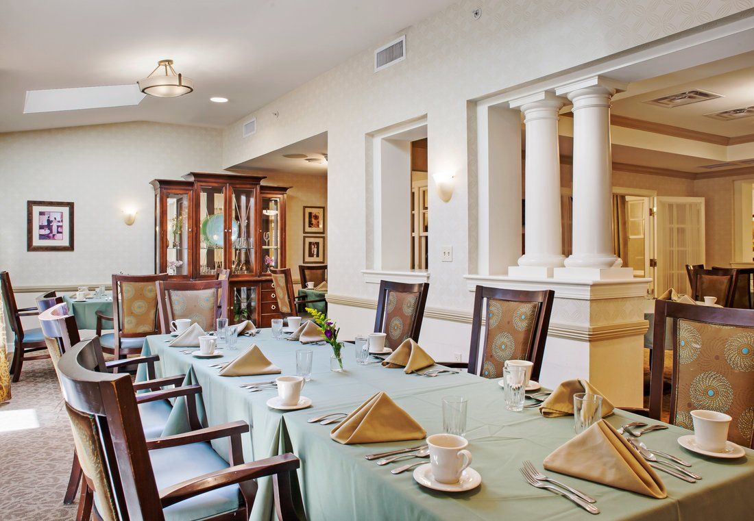An elegantly set dining room with a long table, neatly arranged chairs, and classical decor.