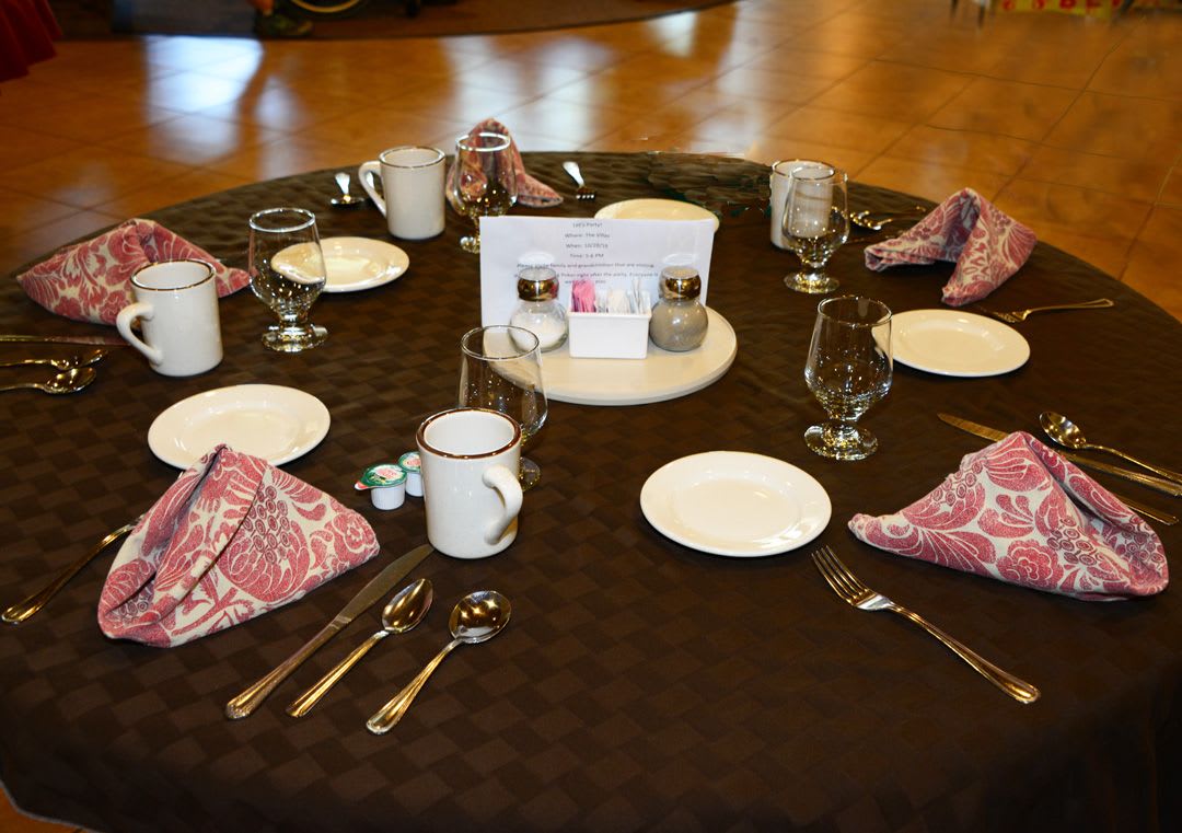 An elegantly set dining table with plates, cutlery, glasses, and folded napkins.