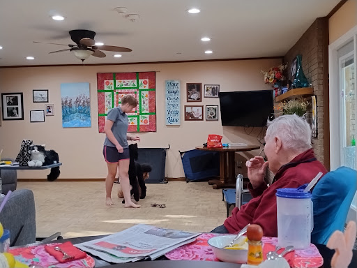 A young woman performs in front of an audience at a community center, engaging the elderly resident.