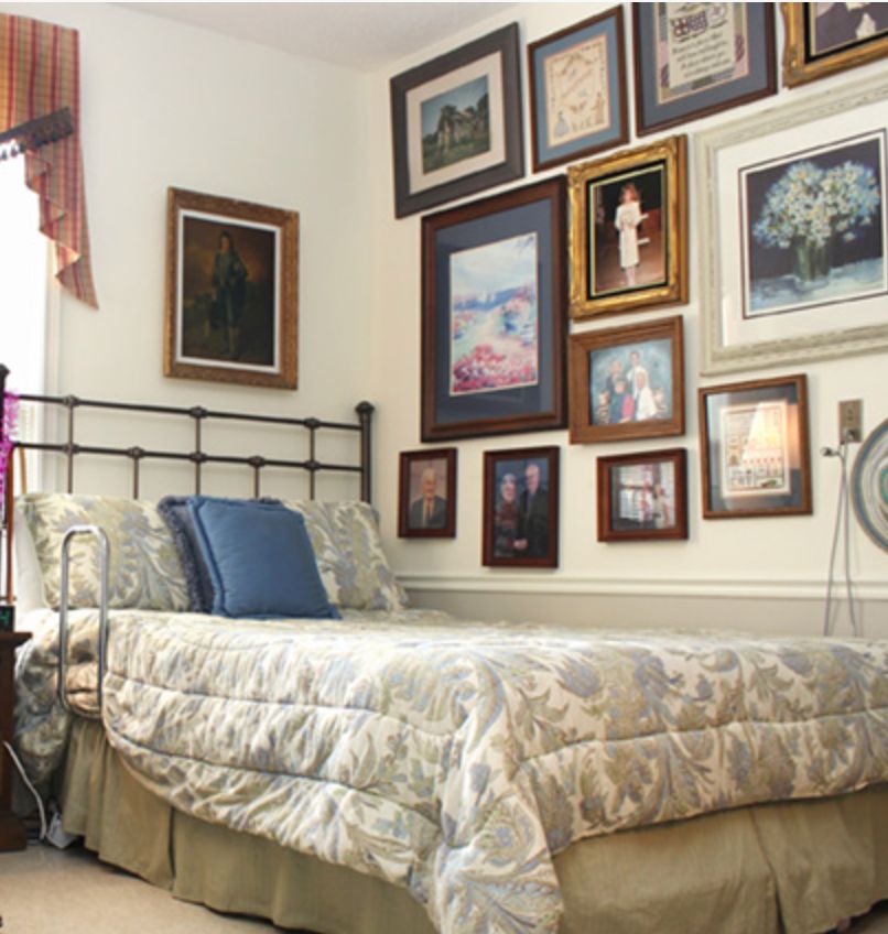 A cozy bedroom decorated with a collection of framed paintings on the wall.