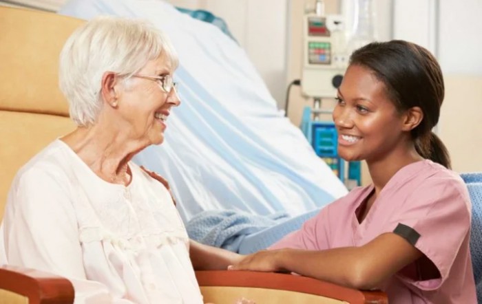 A nurse engaging with an elderly patient in a healthcare setting.