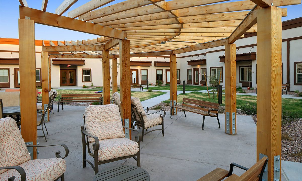 A spacious outdoor patio area featuring a wooden pergola and comfortable seating.