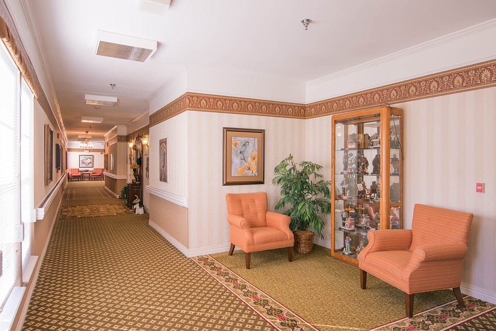 A well-decorated hallway with comfortable chairs, a display cabinet, and wall art.