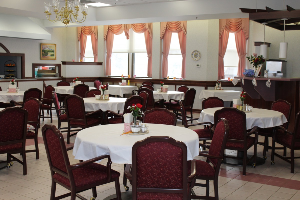 An elegant dining room with several tables covered in white tablecloths and adorned with flowers.