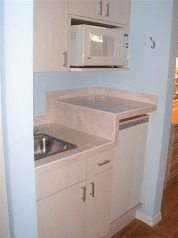 A compact kitchen area with a sink, microwave, and cabinets.