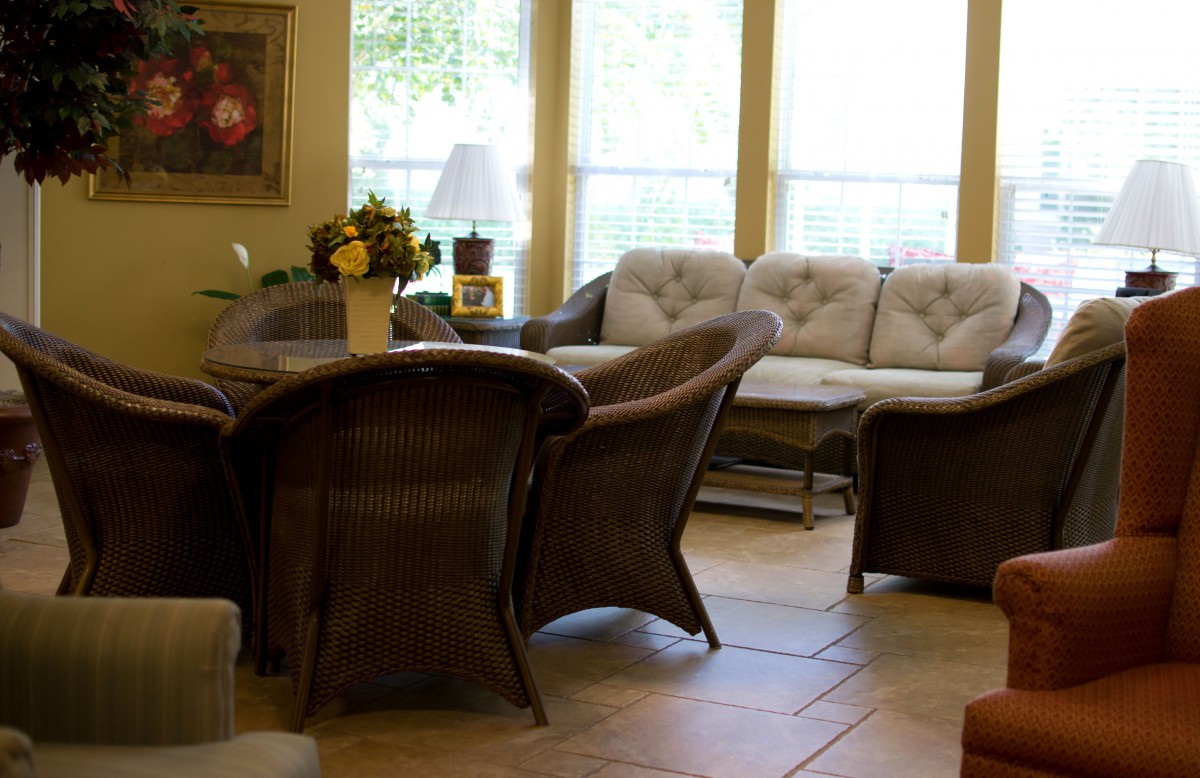 A cozy living room featuring a sofa set, a round table with chairs, and natural lighting from large windows.