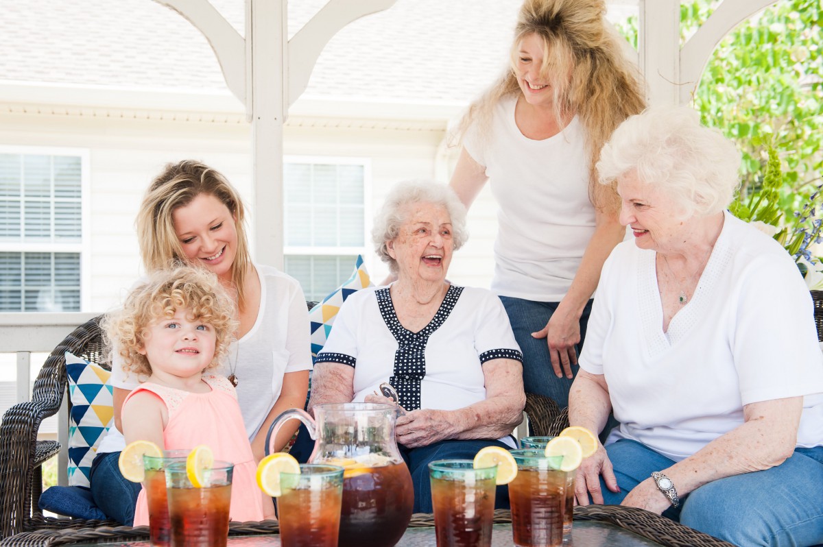 A joyful family gathering with multiple generations enjoying iced tea together outdoors.