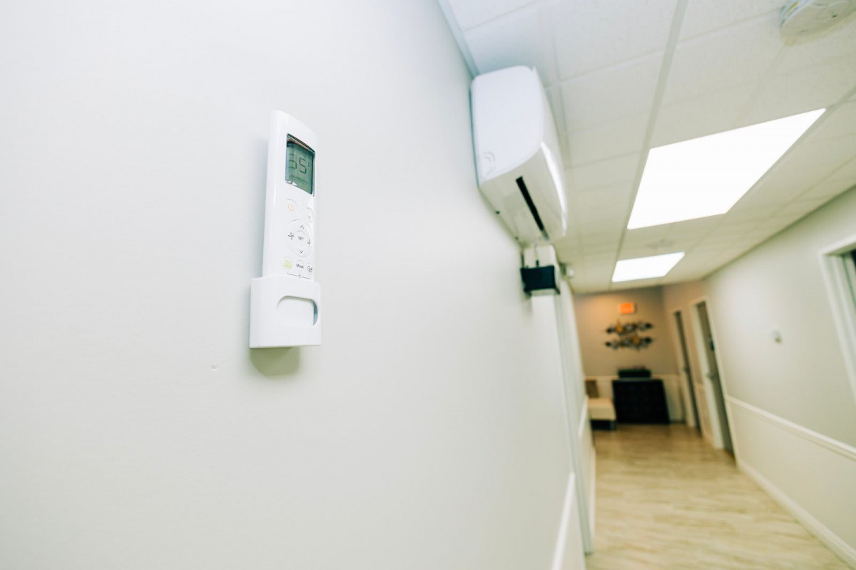 A hallway with a wall-mounted air conditioner and its remote control.
