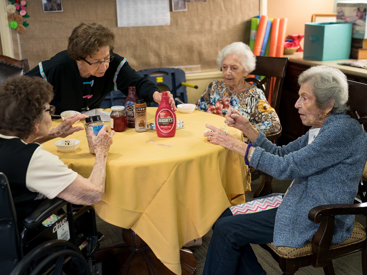 A group of elderly women sitting at a table engaging in conversation.