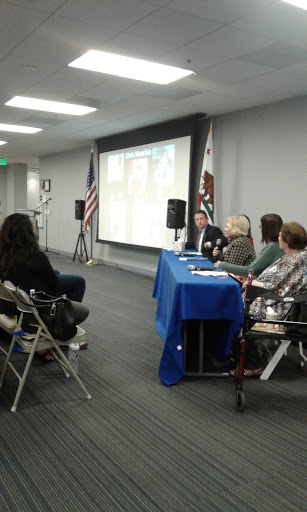 A panel discussion taking place with speakers at a table and an audience in attendance.