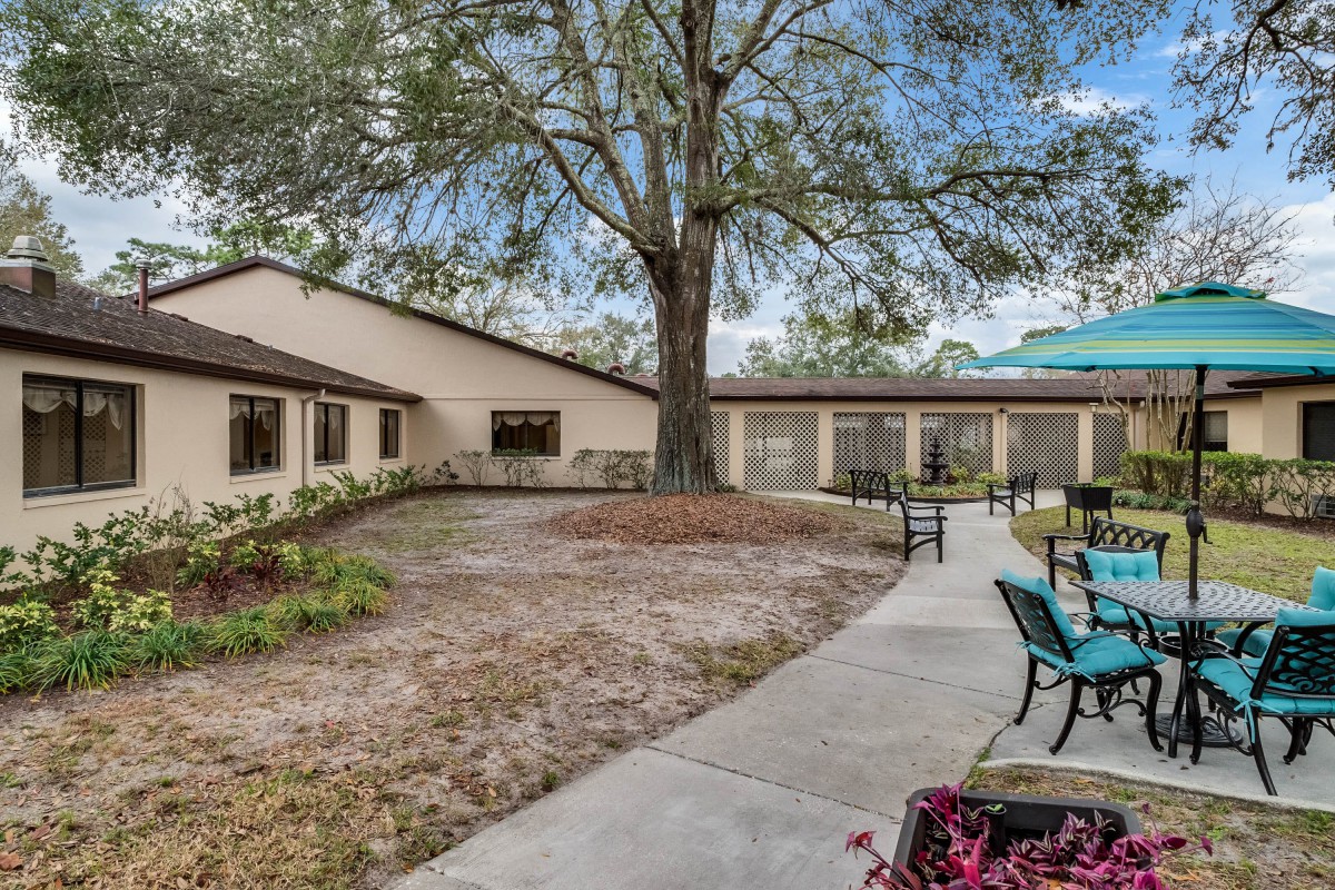 A serene courtyard with outdoor seating and pathways surrounded by trees.