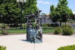 A bronze sculpture displayed outdoors in a park setting.