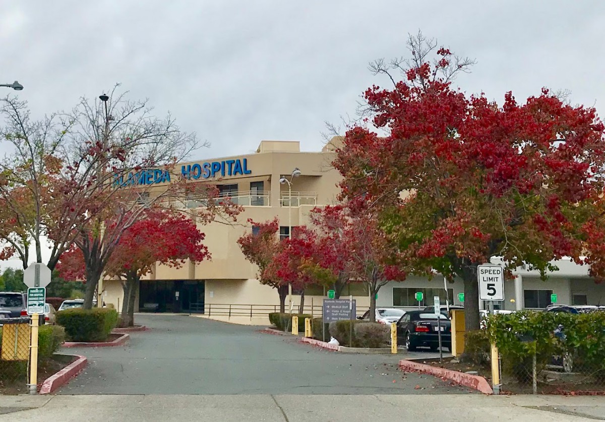 Hospital entrance with vibrant autumn trees and a parking lot.