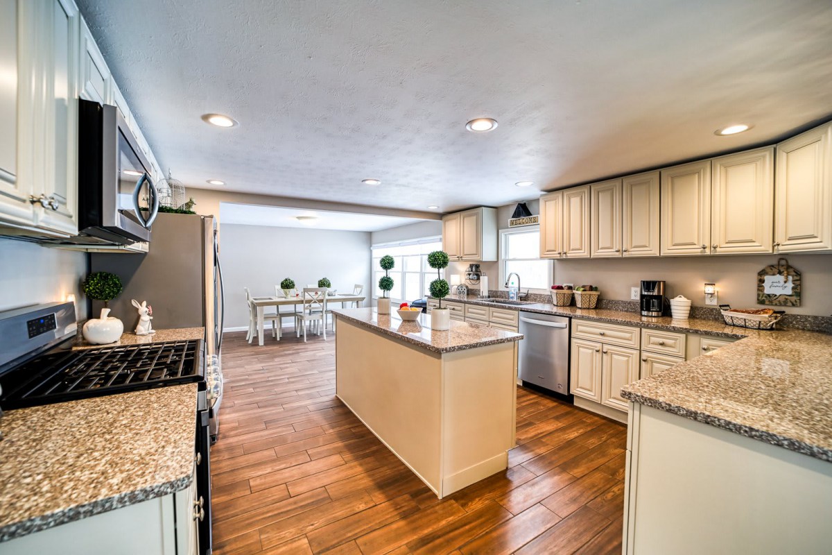 A modern kitchen with an island, wood flooring, and adjacent dining area.