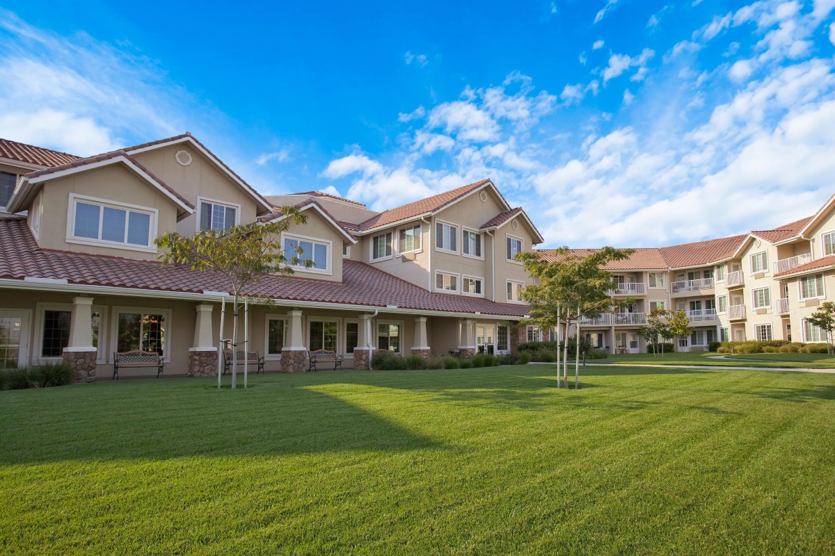 A spacious residential building with well-maintained lawns and clear blue skies.
