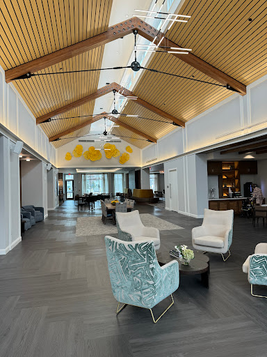 A modern lounge area featuring stylish furniture and a high wooden ceiling.