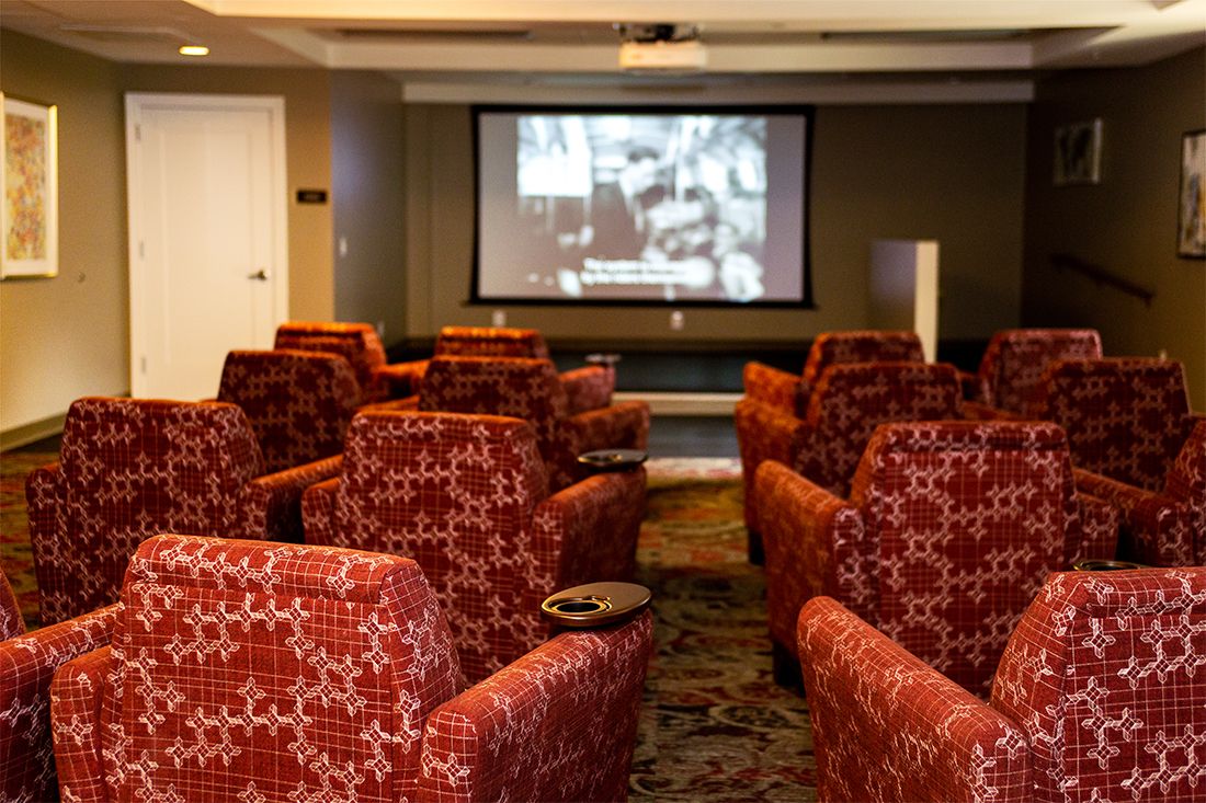 A cozy home theater with red upholstered seating and a large screen.