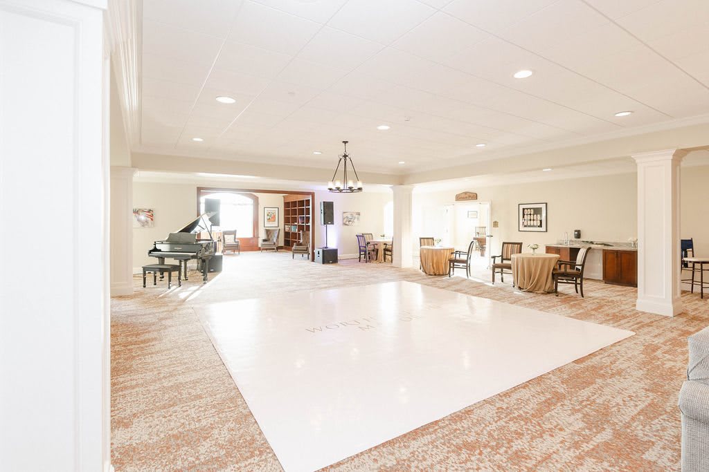 A spacious and elegantly designed living room with a grand piano, dining area, and chandelier.