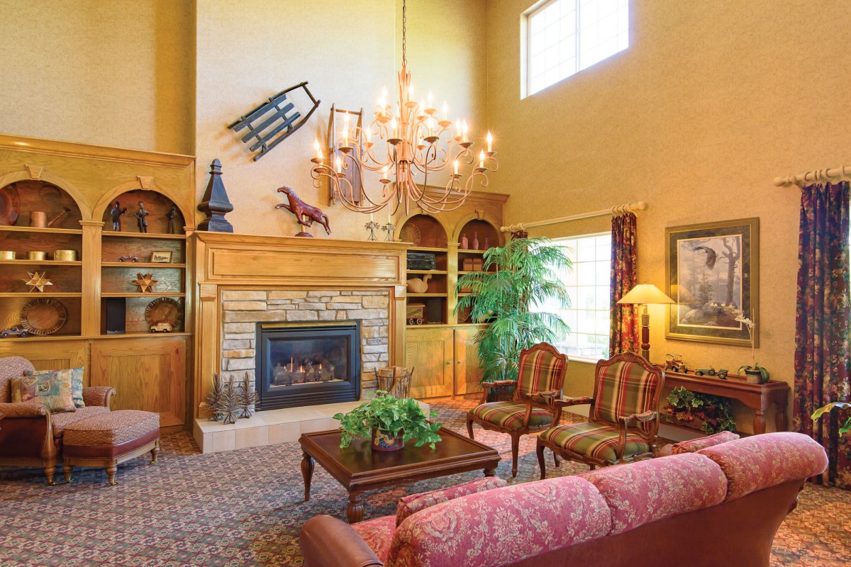A spacious living room with a traditional design, featuring a fireplace, chandelier, and elegant furniture.