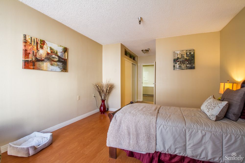 A cozy bedroom with a neatly made bed, wooden flooring, and decorative wall art.