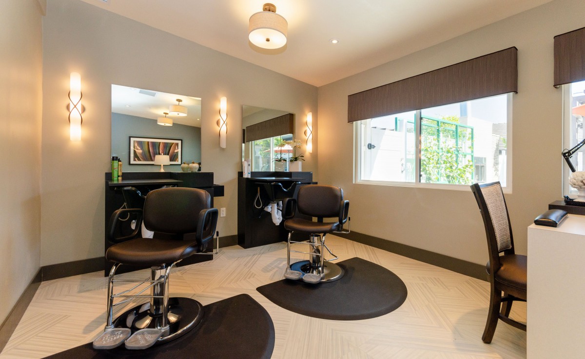 A modern hair salon interior with two barber chairs, mirrors, and stylish lighting.