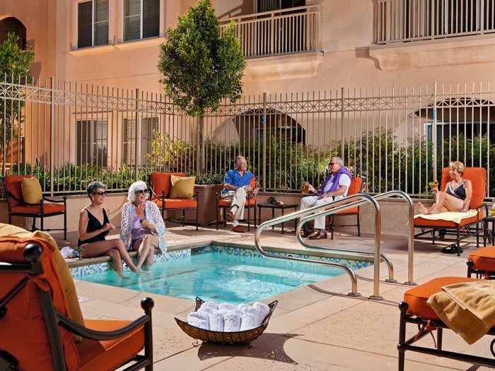 A group of people relaxing by a small outdoor pool on a sunny day.