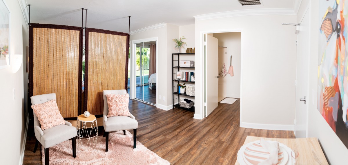 A modern living room with wood flooring, a stylish chair, and an open shelving unit.