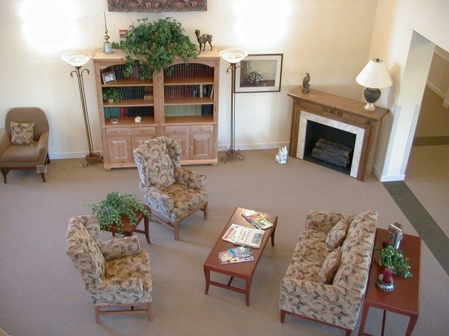 A cozy living room with patterned chairs, a sofa, a wooden table, and a fireplace.